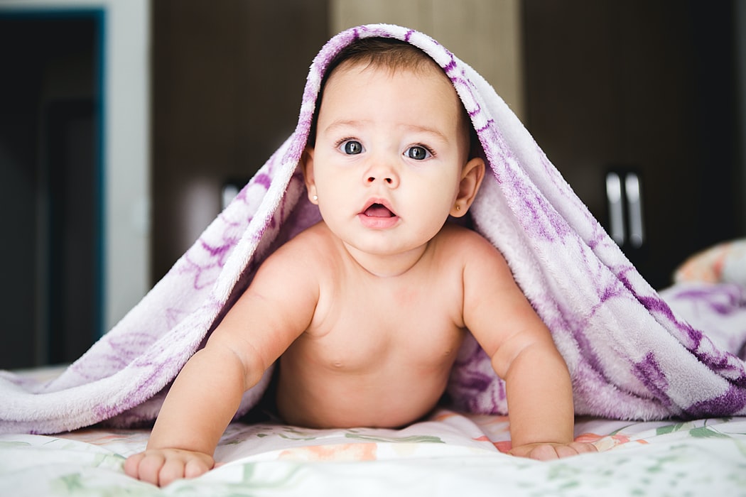 baby looking at camera with banket draped over its head