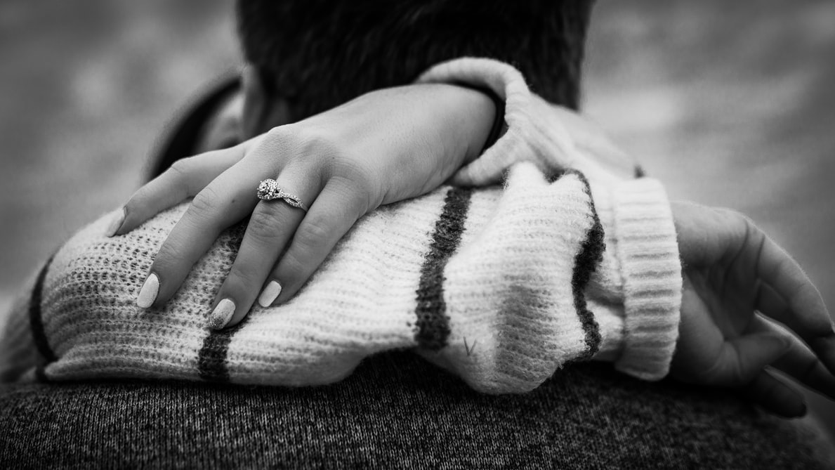 greyscale photo of woman's arms around man